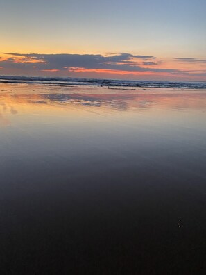 Une plage où l’eau est calme et reflète le ciel.