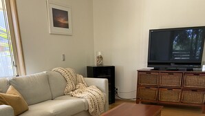 Ein Wohnzimmer mit einer Couch, einem Couchtisch und einem Fernseher auf einem Schrank.