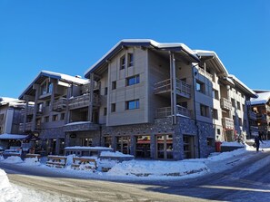A multi-story hotel with balconies, stone facade, and outdoor seating areas.