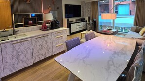 Eine moderne Küche mit Marmorarbeitsplatte, integriertem Backofen und Essbereich mit Glastisch.