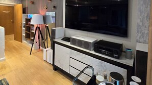 Ein modernes Wohnzimmer mit einem Flachbildfernseher, einer Kaffeemaschine und einer Soundsystem.