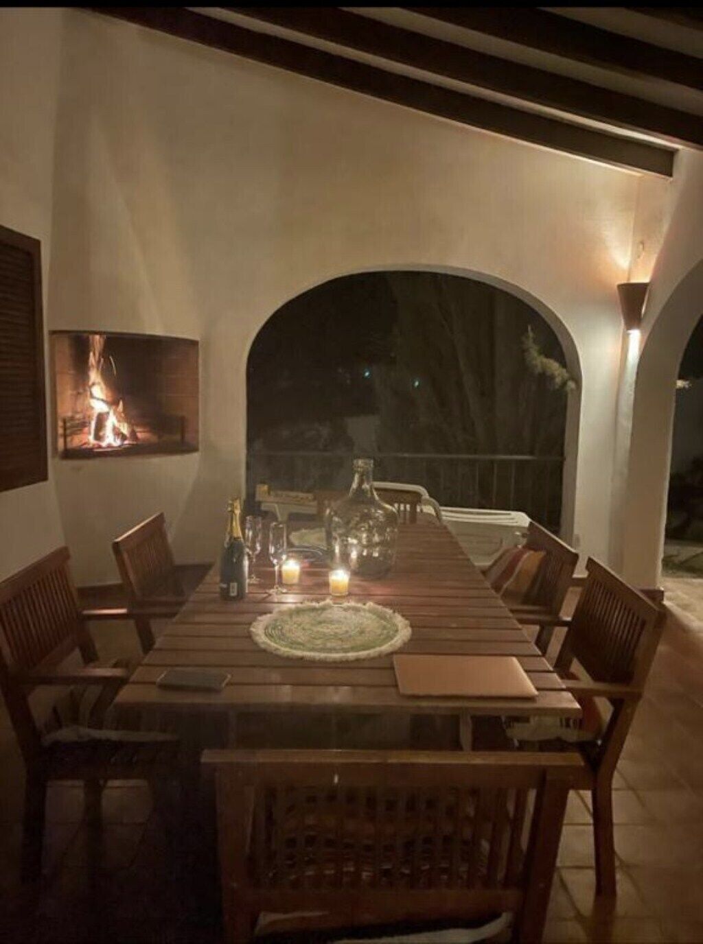A dining area with a long table, chairs, and a fireplace.
