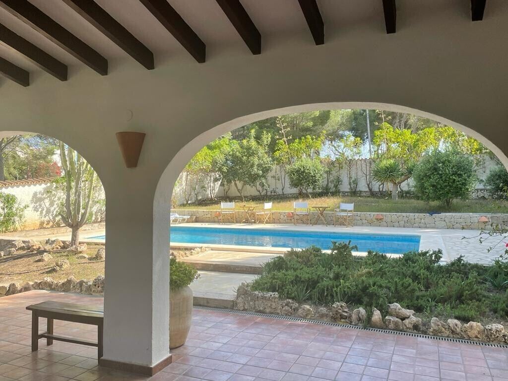 A covered outdoor area with a pool, benches, and a view of the surrounding landscape.