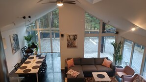 A spacious living area with a large window, a dining table, a sofa, and a ceiling fan.