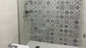 Um banheiro com chuveiro, vaso sanitário e pia.