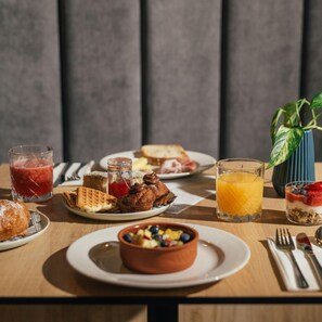A breakfast table with various dishes, drinks, and a plant. - Amery House (Sliema)