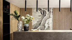 Una zona de recepción con un panel de madera, una pared con textura similar al mármol y una lámpara colgante moderna.