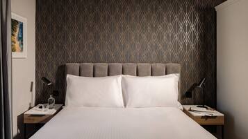 A neatly made bed with a headboard, two bedside tables with lamps, and a framed picture on the wall.