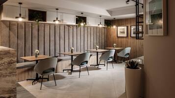 Un restaurante moderno con paneles de madera, iluminación colgante y una variedad de opciones de asientos, incluyendo mesas y sillas.