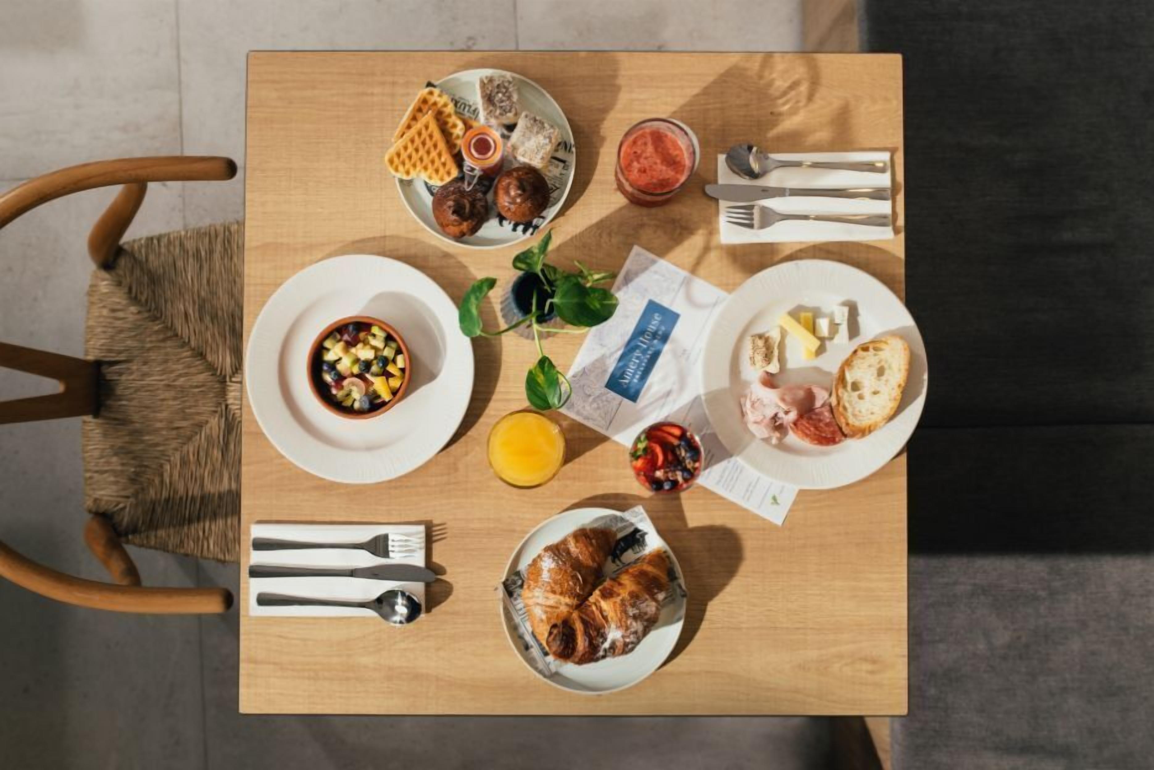 Une table de petit-déjeuner avec des assiettes remplies de nourriture, des couverts et un menu.