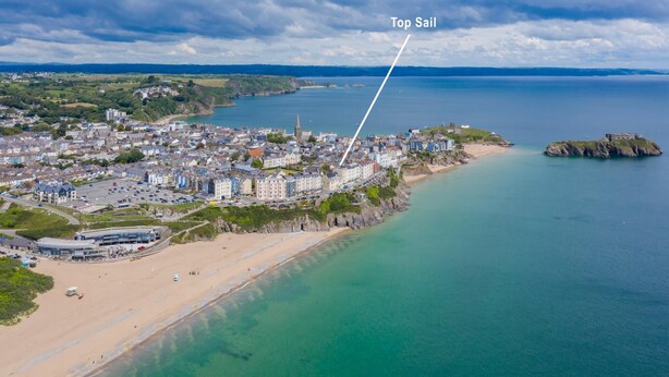 Ett flygbildsbild av en kuststad med ett framträdande hotell som är markerat med namnet ”Top Sail” och som ligger nära stranden.