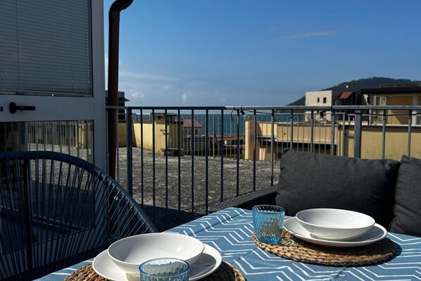 Un espacio de comedor al aire libre con una mesa dispuesta para dos, con vistas a un paisaje urbano.