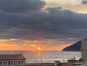 Vista de un atardecer costero con edificios en primer plano.