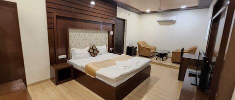 Una habitación de hotel moderna con una cama grande, un escritorio, una silla y un televisor.