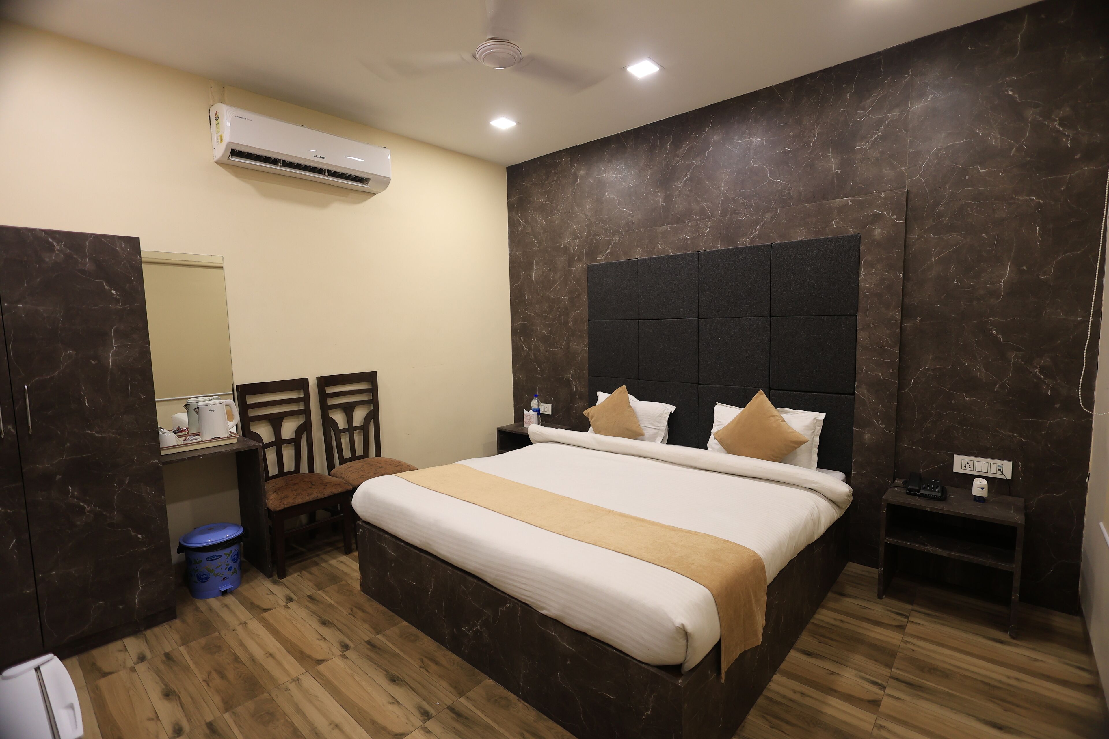Une chambre d’hôtel avec un grand lit, une commode, une petite table et un climatiseur fixé au mur.