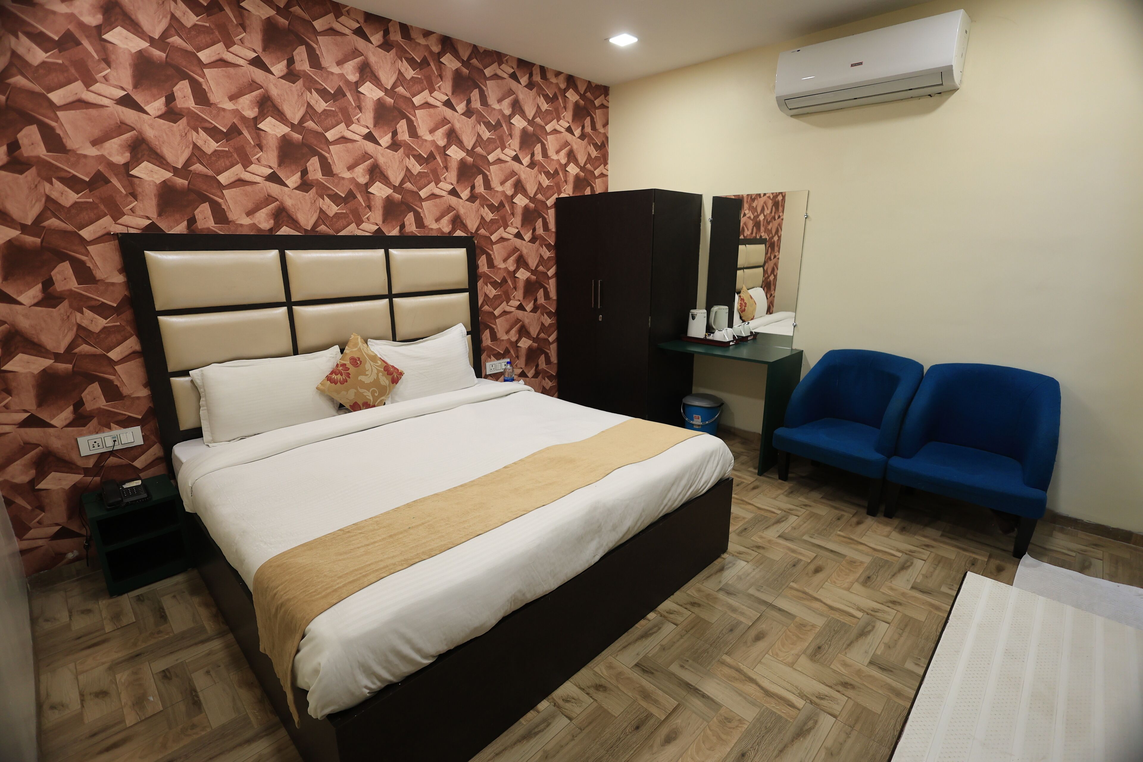 Quarto de hotel com cama, guarda-roupa, escrivaninha e um sofá azul.