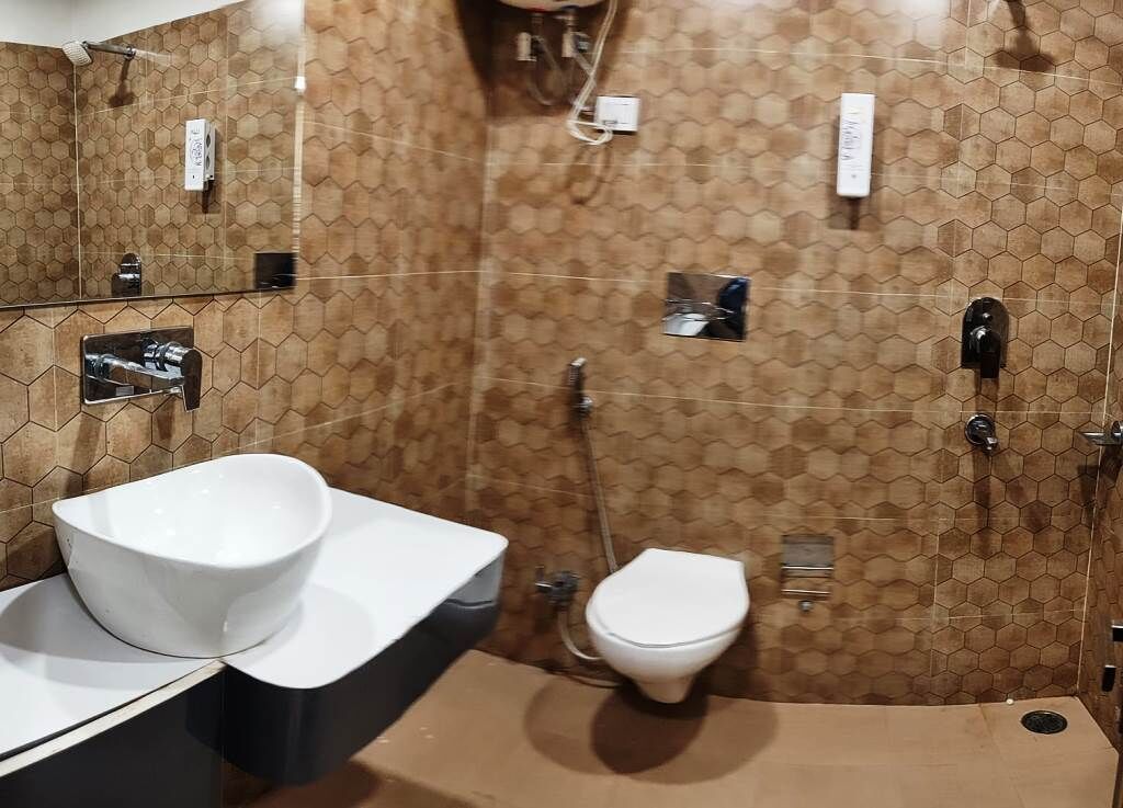 A bathroom with a hexagonal tile pattern, a white sink, a toilet, and a shower area.