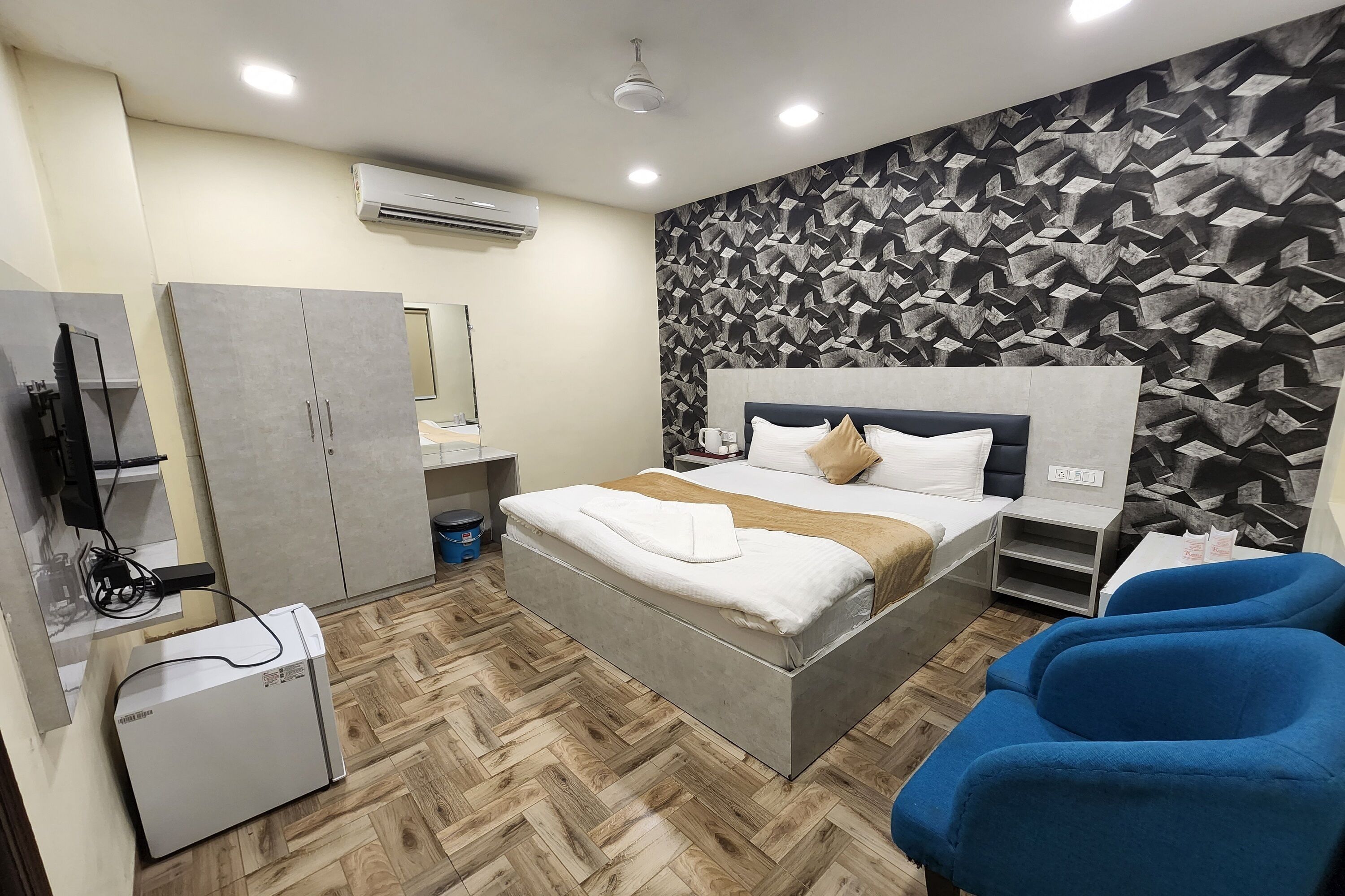 A modern bedroom with a bed, a wardrobe, a desk, and a blue chair.