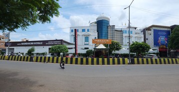 A building with a sign for 'Hotel Mandakini Royale' and 'Rooms Banquets Restaurant Bar Gym'.