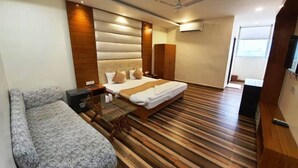 Een moderne hotelkamer met een bed, een bank, een houten vloer, een plafondventilator en een airconditioning.