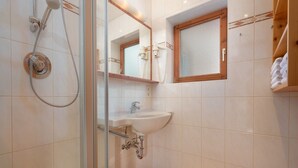 Une salle de bain avec une douche à parois de verre, un lavabo, un miroir et une fenêtre.