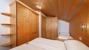 Camera da letto con pareti e soffitto in legno, due letti e armadi a muro.