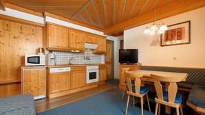 Una cucina compatta con mobili in legno, un forno a microonde, un piano cottura e un'area pranzo con tavolo e sedie.