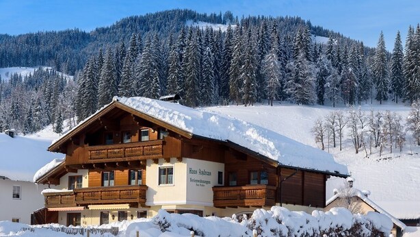 Una baita di legno con un cartello che riporta la scritta "Haus Andreas" in una zona montana innevata.