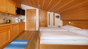 A bedroom with a wooden ceiling, a bed, and a kitchenette with wooden cabinets and a television. - Cozy Studio #5 - 5 mins to ski lift (Flachau)