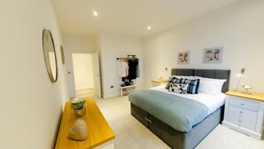 Une chambre moderne avec un lit, des tables de chevet, un banc en bois et une armoire.