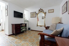 Um quarto com cama, cômoda, televisão, espelho e luminária.