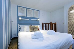 Quarto de hotel com cama, almofadas, cabeceira e certificados emoldurados na parede.