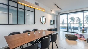 A modern meeting room with a wooden table, black chairs, a large window, and a view of the outdoors. - luxury garden apartment heated pool (Tiberias)