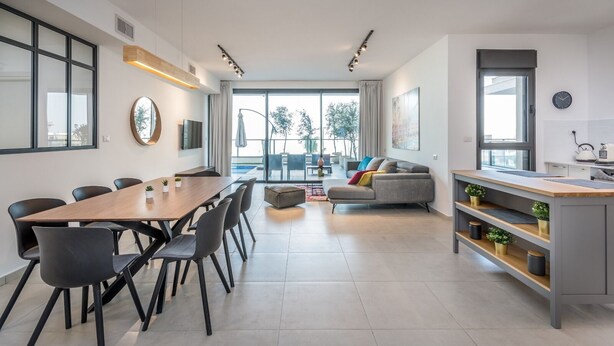 A modern kitchen with a dining area, a sofa, and a kitchen island. - luxury garden apartment heated pool (Tiberias)