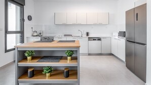 A modern kitchen with white cabinets, a wooden island, and stainless steel appliances. - luxury garden apartment heated pool (Tiberias)