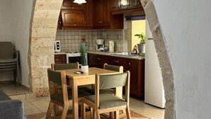 Un espace repas agrémenté d’une arche en pierre qui mène à la cuisine.