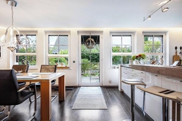 A modern kitchen with a dining area, large windows, and a chandelier. - Let your soul dangle. (Rees)