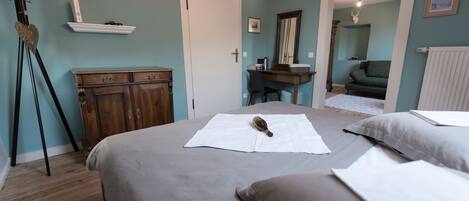A bedroom with a bed, a dresser, a desk, and a mirror.