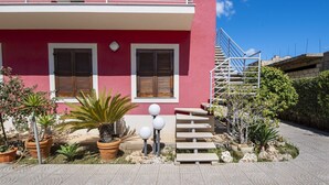 A red building with two windows, a staircase, and potted plants. - Villa Tonnara 50m dal mare (Avola)