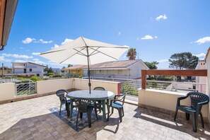 Un patio con una mesa redonda y sillas, una sombrilla y vistas a edificios cercanos.