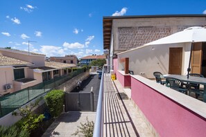 Un balcón con mesa y sillas, una reja y vistas a edificios cercanos.