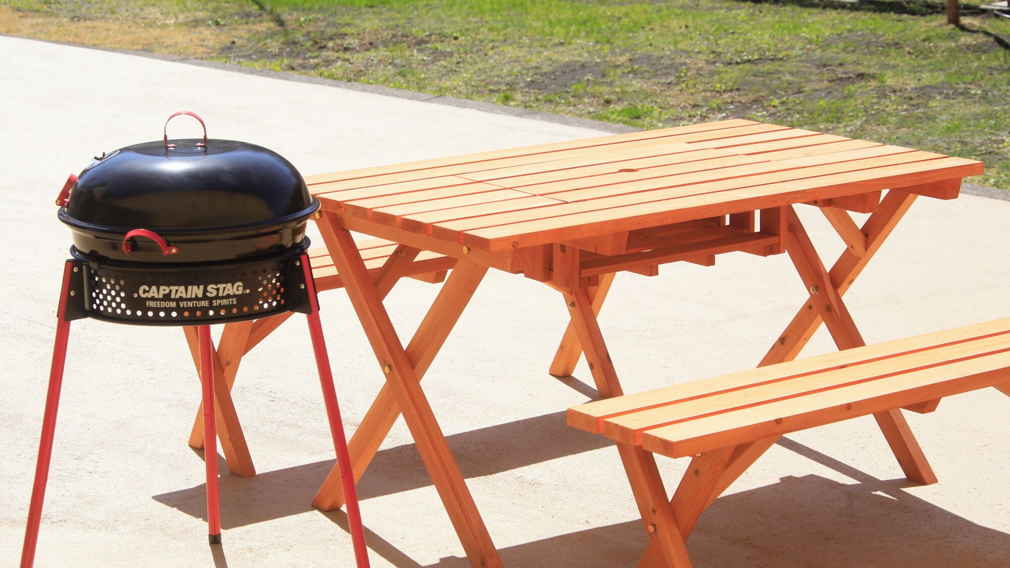 Ein tragbarer Grill mit Deckel und Tisch mit Bänken.