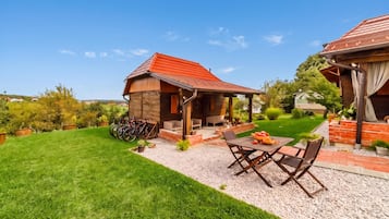 Una casa de madera con techo rojo, un patio con mobiliario exterior y un césped bien cuidado.