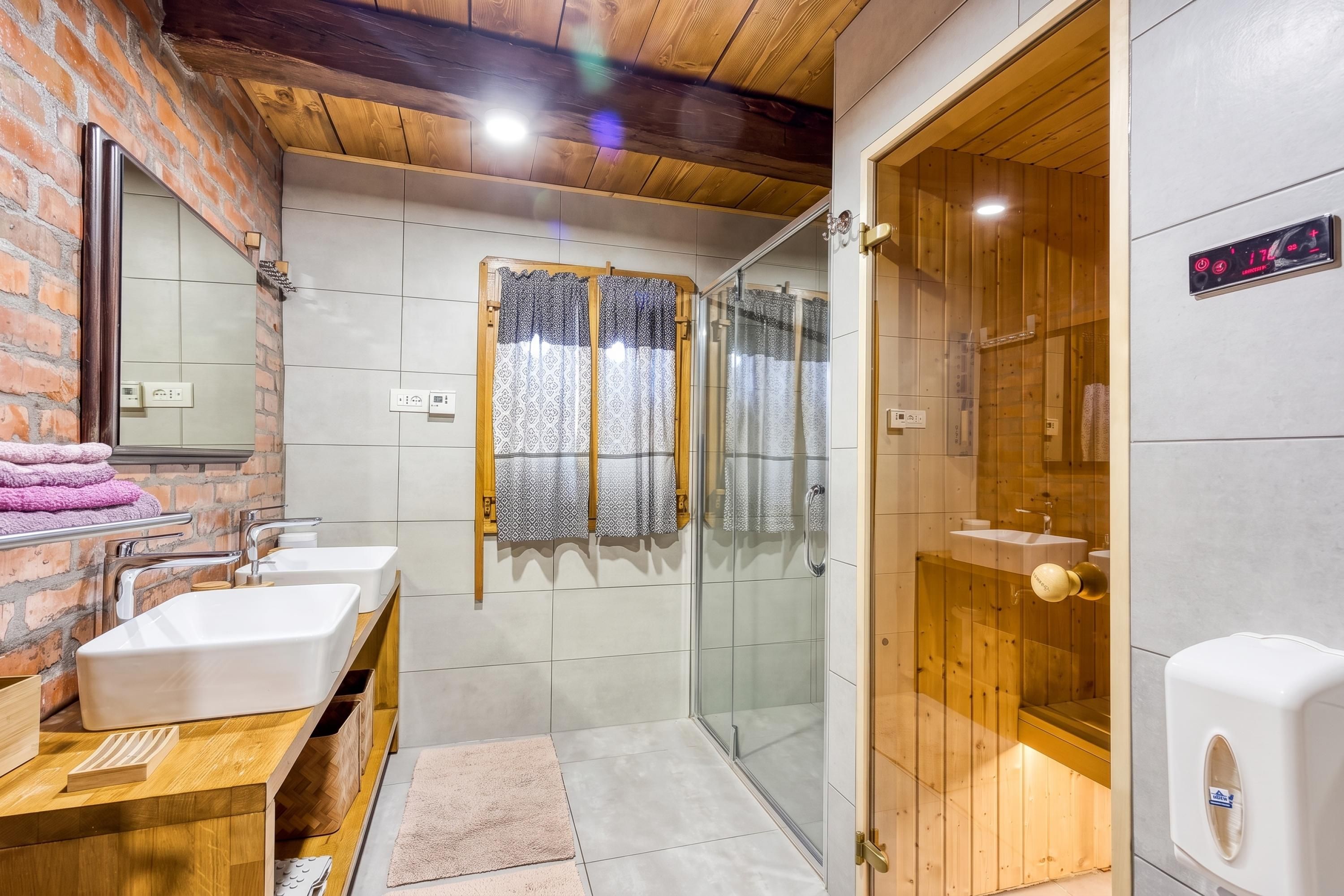 A bathroom with two sinks, a shower enclosure, and a wooden door.
