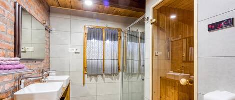 A bathroom with two sinks, a shower enclosure, and a wooden door.