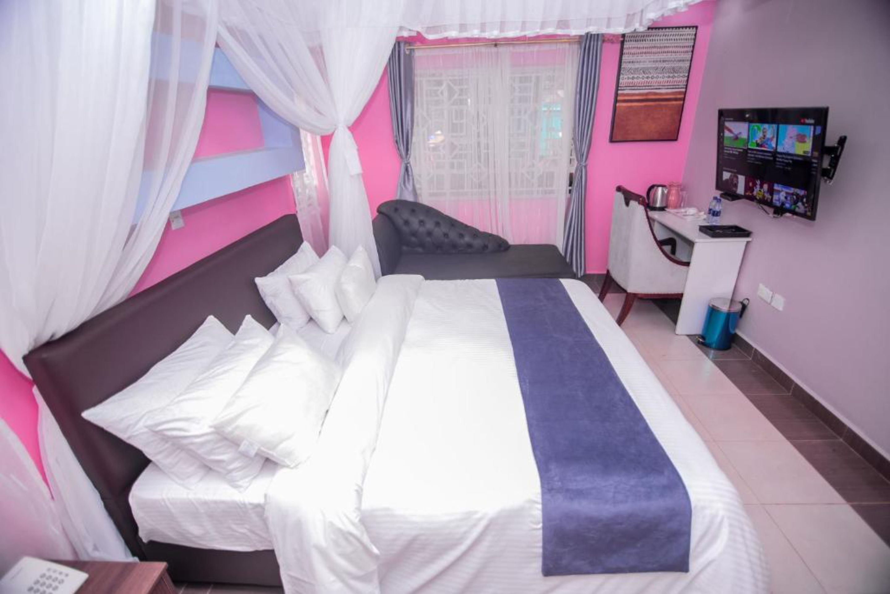 A bedroom with a bed, a desk, and a television.