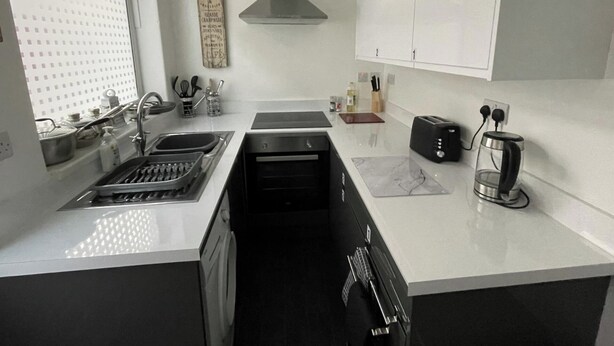 A modern kitchen with a stainless steel sink, a built-in oven, a toaster, and a coffee maker. - 3 Bed House - Sleeps 5 - Wifi, Parking (Darlington)