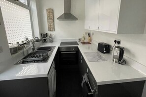 A modern kitchen with a stainless steel sink, a built-in oven, a toaster, and a coffee maker. - 3 Bed House - Sleeps 5 - Wifi, Parking (Darlington)