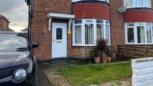 A two-story brick house with a white front door, a satellite dish, and a car parked in the driveway. - 3 Bed House - Sleeps 5 - Wifi, Parking (Darlington)
