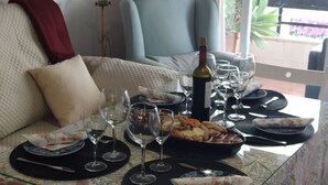 A dining table set with wine glasses, plates, and a bottle of wine, with a sofa and chair in the background. - Apartment right on the beach (Playa de Isla Canela)